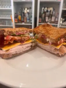 Toasted turkey club sandwich halved on plate