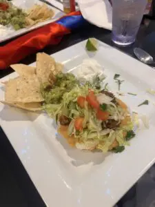 Tostada with beef, lettuce, guacamole and chips
