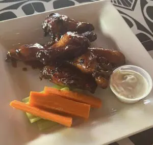 Glazed chicken wings with carrots, celery, dip